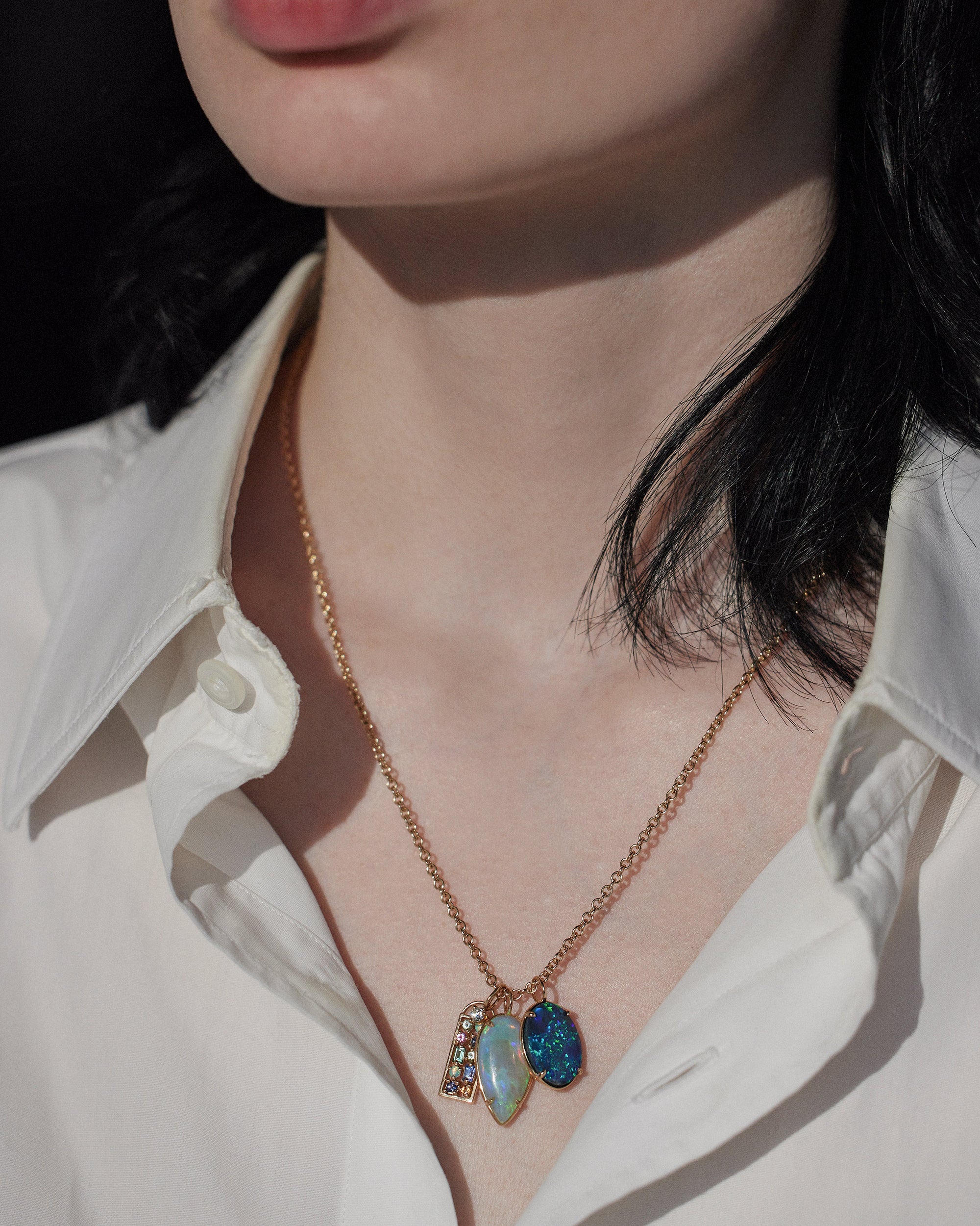 [lifestyle] Necklace with a blue pendant worn by a person in a white shirt.