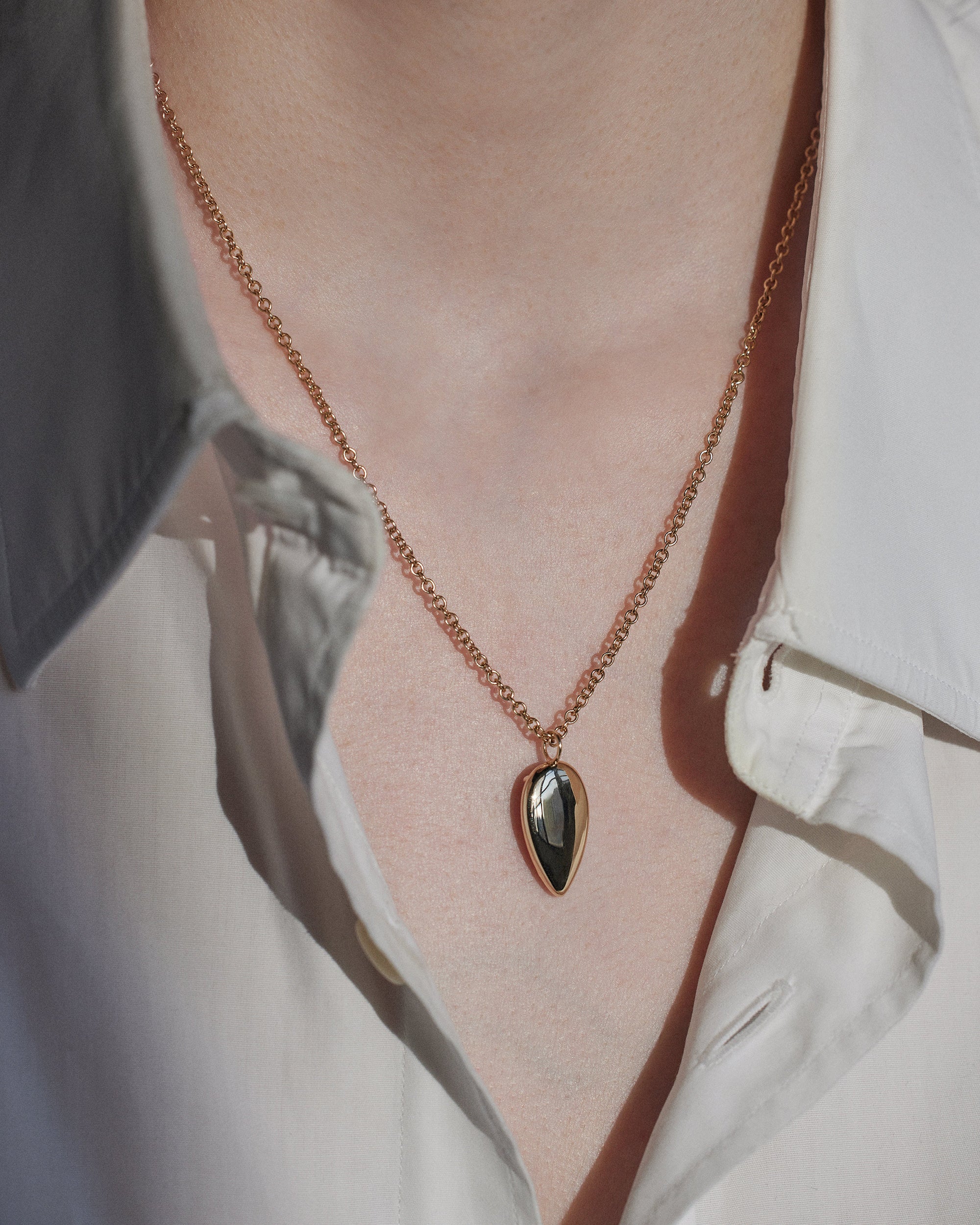 [lifestyle]Necklace with a pendant worn by a person, focusing on the jewelry.