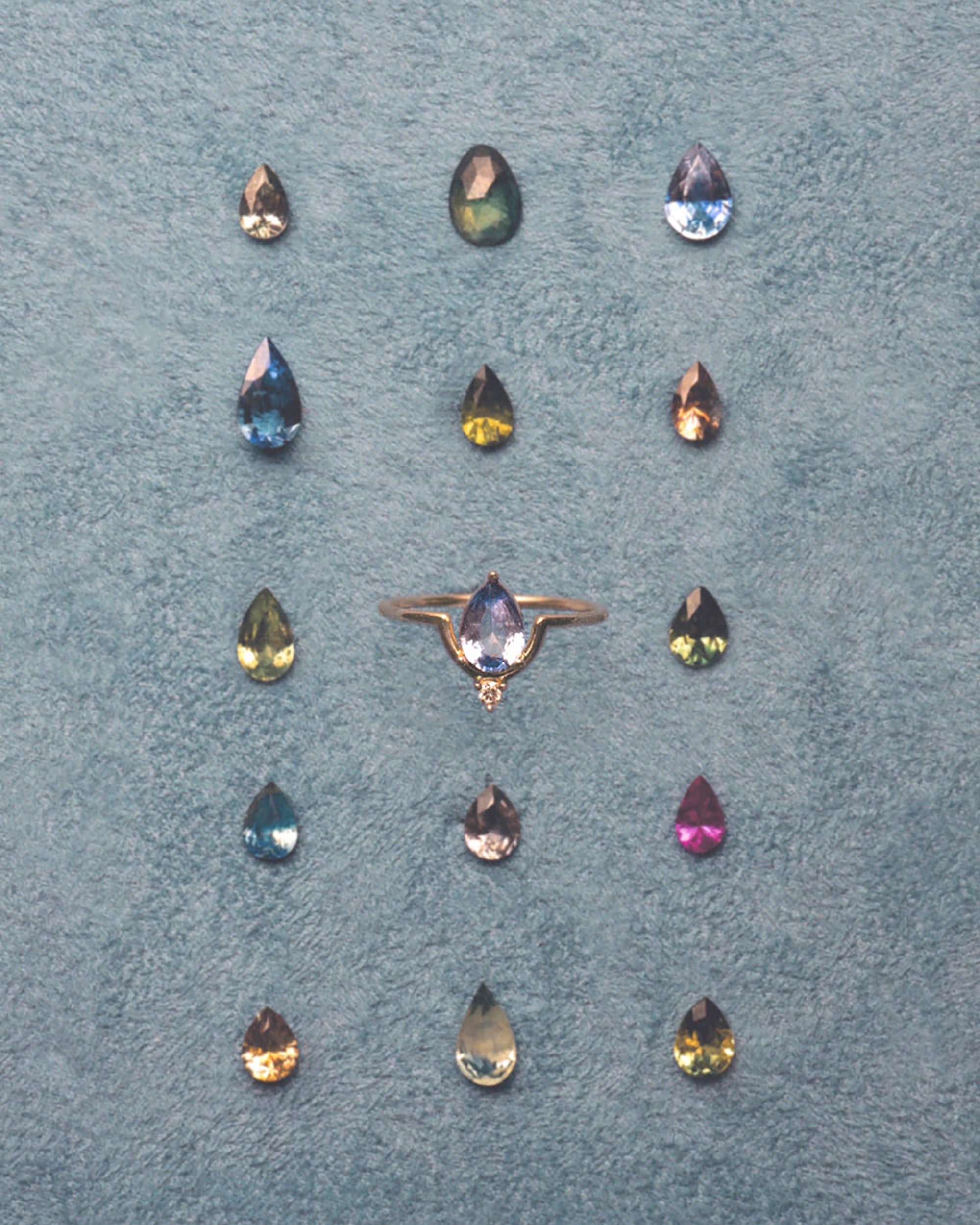 [lifestyle]Ring with multicolored gemstones on a textured blue surface